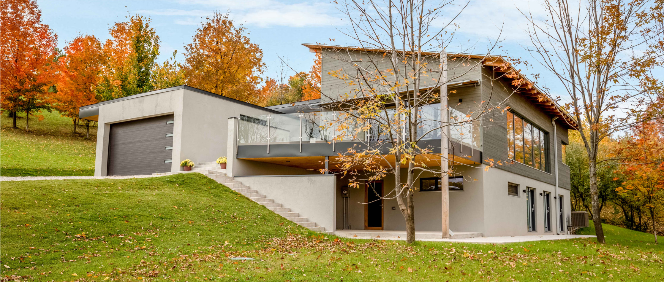 Exterior of a multi-storey house with garage second-floor patio, surrounded by trees in the fall.
